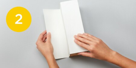 person folding paper around a box
