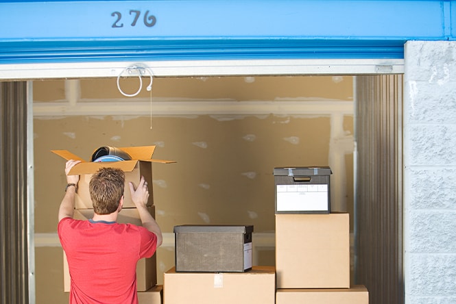 A person loading a storage unit with cardboard boxes.

