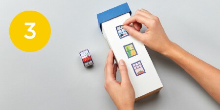 person putting washi tape on box wrapped with paper
