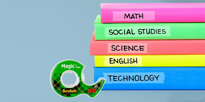 Scotch® Magic™ Tape in front of a stack of labeled classroom notebooks.
