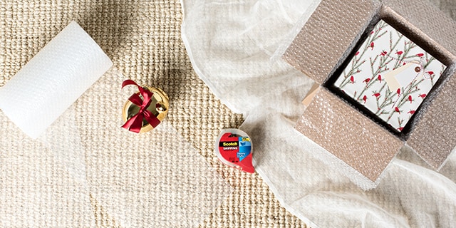 Un cadeau, du tulle et du ruban de marque Scotch® sur une surface en tissus.
