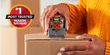 a person using Scotch® Box Lock™ tape to seal a cardboard box.
