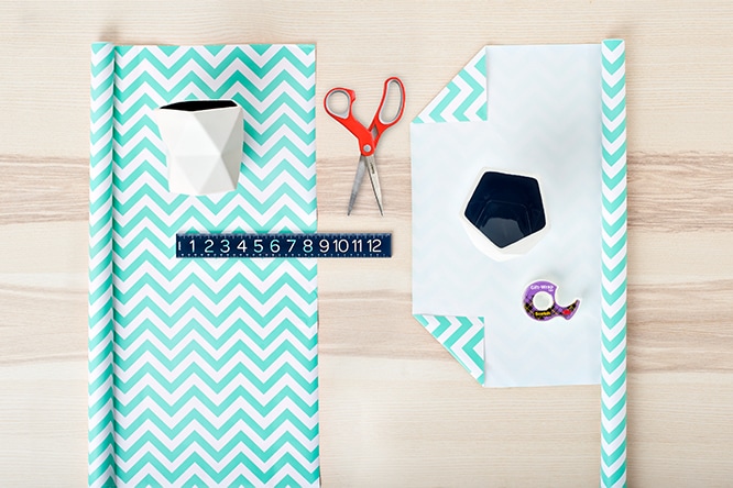 Craft setup with turquoise chevron paper, scissors, ruler, and geometric planter on wood table.
