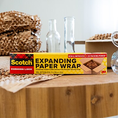 Scotch™ Cushion Lock™ Expanding Paper Wrap sitting on a wooden table next to glass bottles and vases.