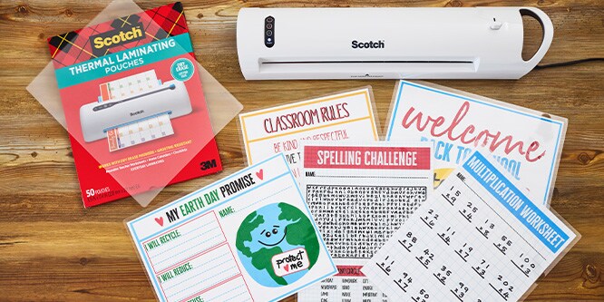 A Scotch Thermal Laminator on a wood table with classroom supplies and Thermal Laminating Pouches.
