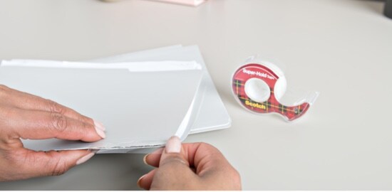 A person applying Scotch® Super-Hold Tape to the bottom of a file folder.
