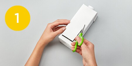 person cutting a rectangle out of a box
