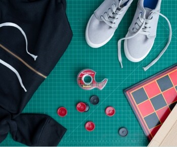 Assorted clothing items, buttons and a roll of Scotch® Super-Hold Tape.