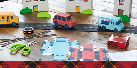 Paper vehicles along a paper road and houses.
