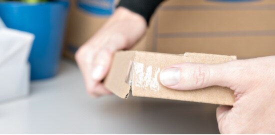 A person holding a box with Scotch® Super-Hold Tape reinforcing the corner.
