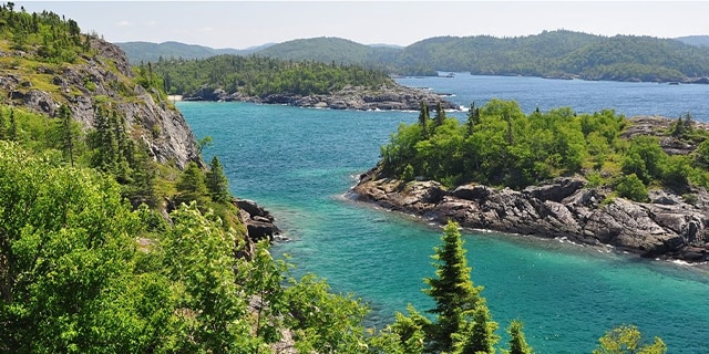 A beautiful lake landscape with green trees, blue water and an island.
