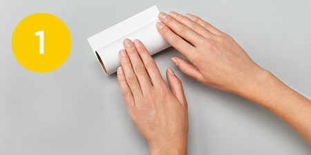 person covering a toilet paper roll with construction paper
