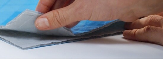 A person pressing together two parts of Scotch™ Flex & Seal Shipping Roll to seal a package.
