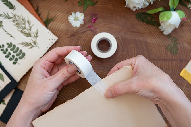 a person writing a custom “rosemary” label on a small jar with fresh rosemary in it.

