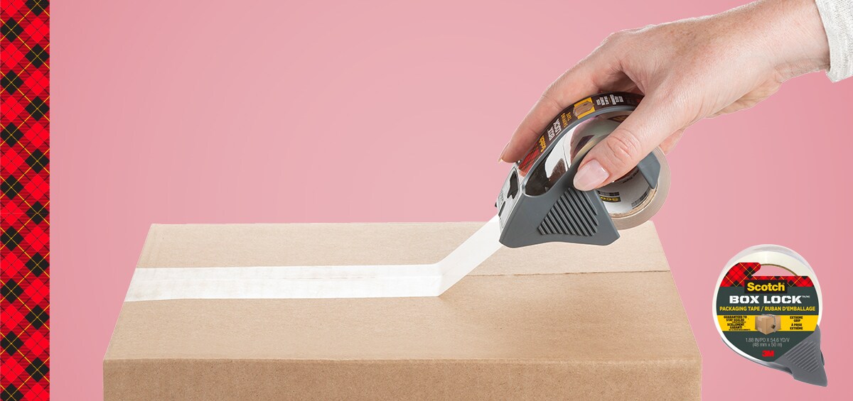 Person safely securing a brown corrugated box with packing tape dispenser using Scotch® Box Lock™ Shipping Tape.
