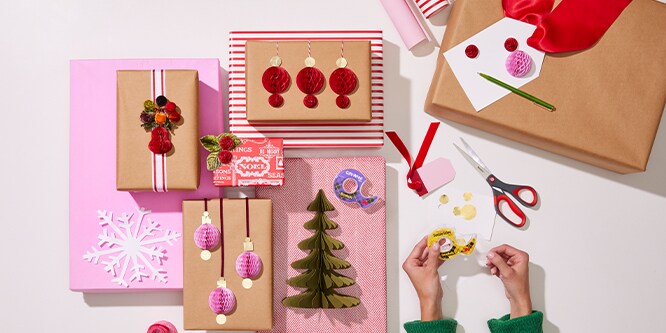 An overhead view of various decorated gift boxes wrapped pink, red, and kraft paper.
