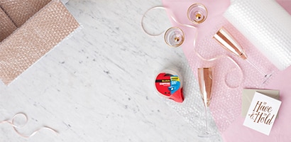 Christmas tree with colorful ornaments and various wrapped gifts beneath, featuring bows and festive patterns.
